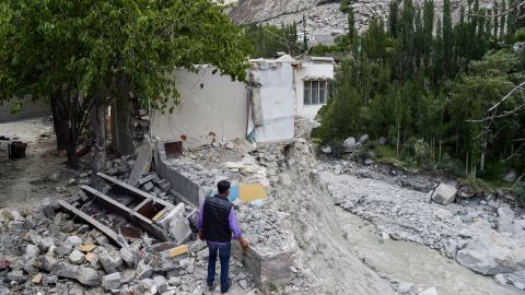 A local resident stands next to his damaged home in June after an eruption of a glacial lake caused catastrophic flooding in the northern Pakistani village of Hassanabad. 