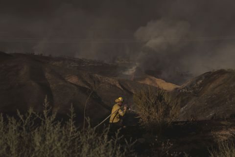 A firefighter hoses down hot spots while battling the Route Fire in Castaic, California, on Wednesday, August 31. <a href=