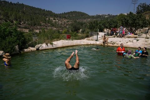 People swim in Jerusalem's Ein Haniya spring during a heat wave on Monday, August 29.