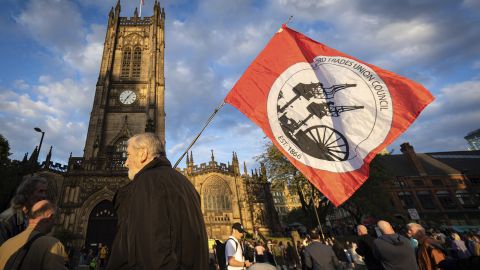 A man with a trade union flag waits at the start of a sold-out campaign event. 