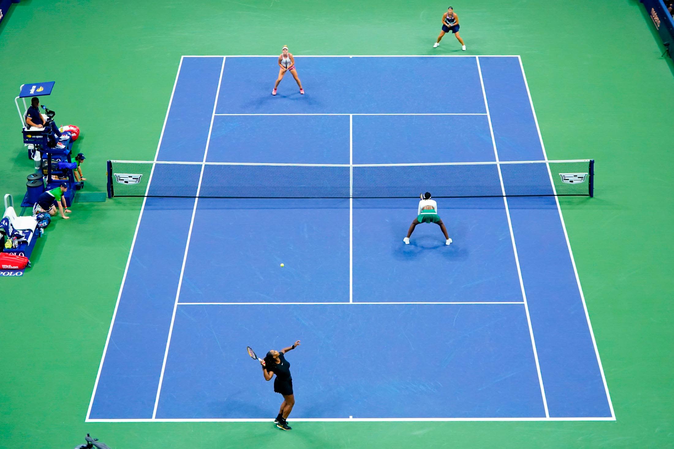 Williams, lower left, serves during Thursday's doubles match.