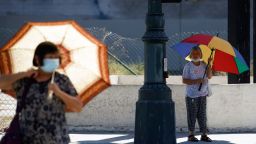 People walk with umbrellas for shade in Los Angeles, California, on Thursday.