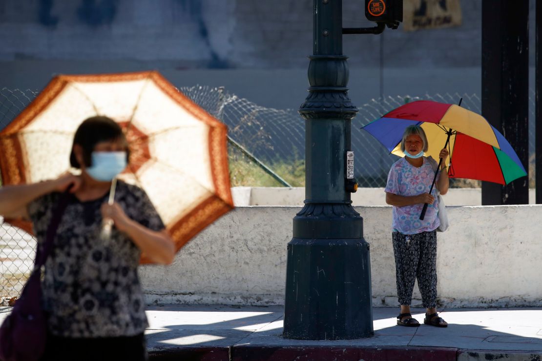 People walk with umbrellas for shade in Los Angeles on Thursday.