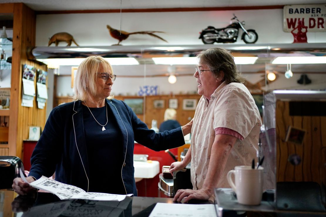 Maine Gov. Janet Mills, left, here chatting with a barber shop owner in Hallowell on May 25, 2022, is being challenged by her predecessor, Republican Paul LePage. 