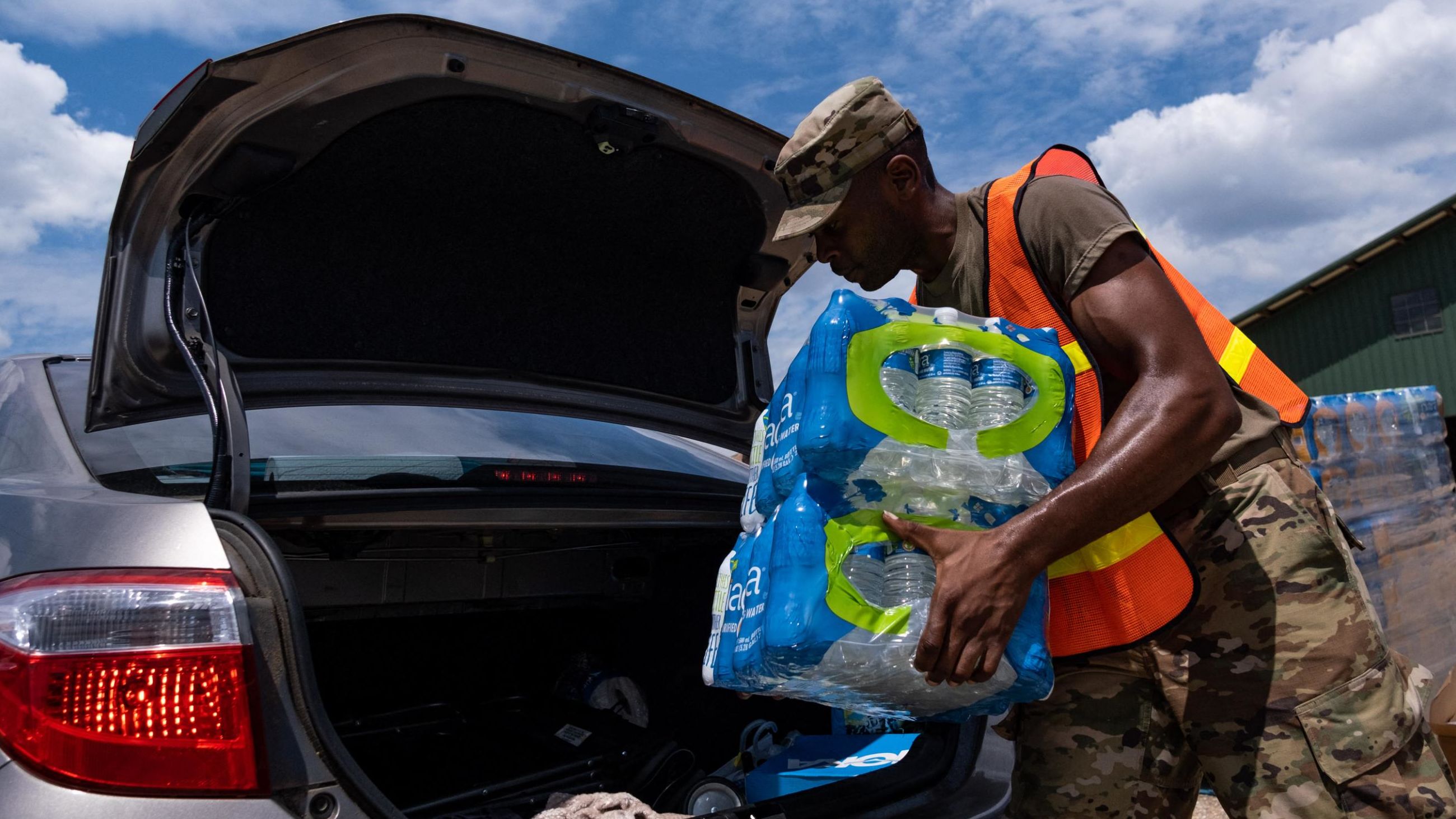 A member of the National Guard places a case of water in the back of a car at the State Fair Grounds in Jackson, Mississippi, on Friday.