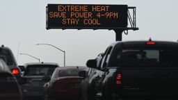 Vehicles drive past a sign on the 110 Freeway warning of extreme heat and urging energy conservation during a heat wave in downtown Los Angeles, California on Friday. 