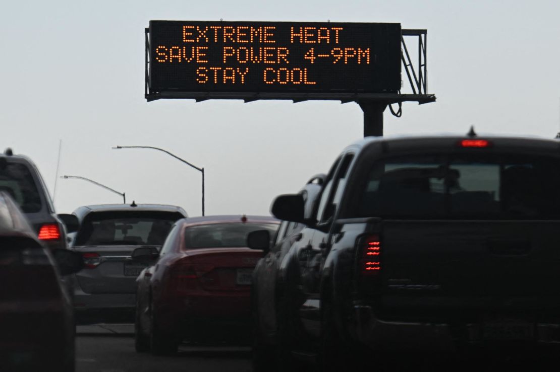 Vehicles drive past a sign on the 110 Freeway warning of extreme heat and urging energy conservation during a heat wave in downtown Los Angeles, California on Friday.