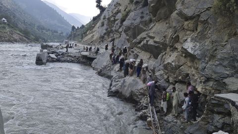 Residents clamber over rocks to avoid flood waters in Kalam Valley, northern Pakistan,  September 4, 2022.