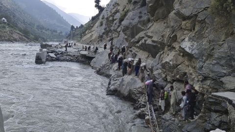 Residents clamber over rocks to avoid flood waters in Kalam Valley, northern Pakistan, September 4, 2022.