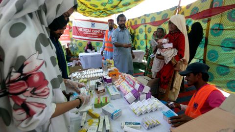 Displaced families wait to receive medicine at a distribution point in Sukkur, Pakistan on September 4, 2022.