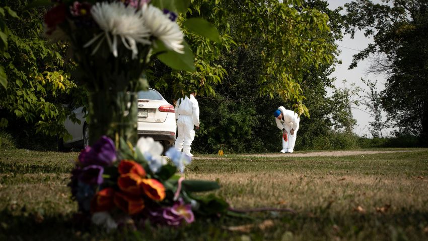 Investigators examine the crime scene near a memorial of flowers in Weldon, Saskatchewan, Monday, Sept. 5, 2022.