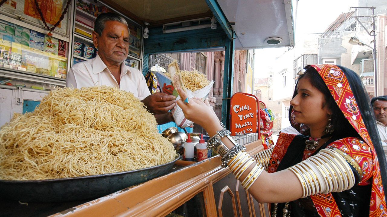 A woman buys bhujia from a street stall in Bikaner, India.