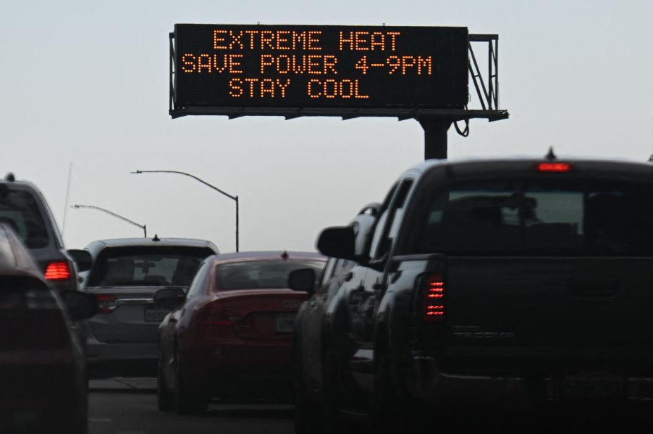 Motorists drive past a highway sign that carried a warning about extreme heat in Los Angeles on Friday, September 2. The sign also urged energy conservation.