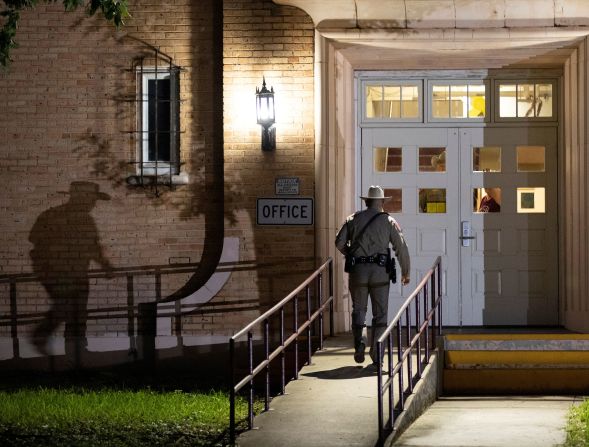 A trooper walks into Flores Elementary School on Tuesday.