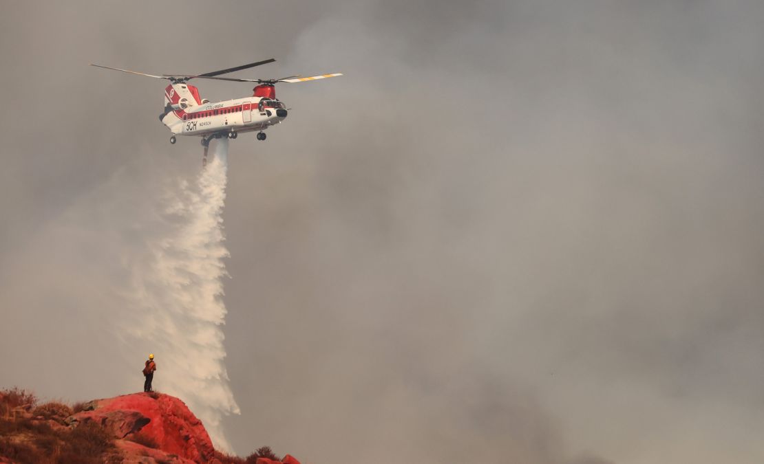 A firefighting helicopter performs a water drop as the Fairview Fire burns Tuesday near Hemet, California. 
