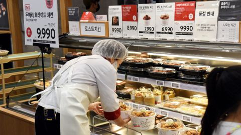 A Homeplus employee is selling buckets of fried chicken.  The hypermarket has created pressure on other stores to follow suit with its popular discounts.