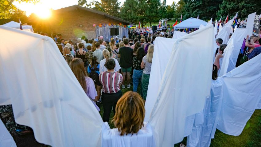 People dressed as "angels" form a wall in an effort to shield counterprotestors as the RaYnbow Collective hosts a Back to School Pride Night for BYU students at Kiwanis Park in Provo, Utah on Saturday, Sept. 3, 2022. (Francisco Kjolseth/The Salt Lake Tribune via AP)