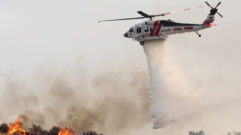 A firefighting helicopter drops water as the Fairview Fire burns on September 7, 2022, near Hemet, California.