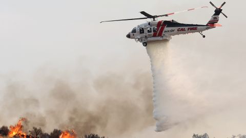 A fire helicopter drops water as the Fairview Fire burns near Hemet, California on September 7, 2022.