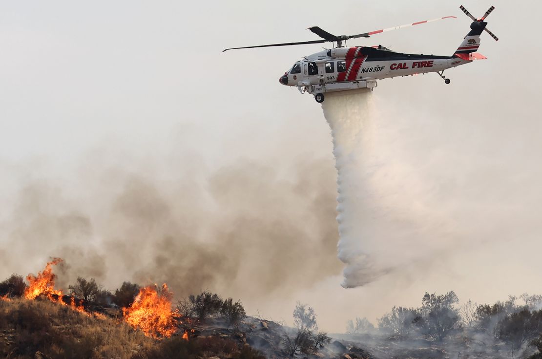 A firefighting helicopter drops water as the Fairview Fire burns on September 7, 2022, near Hemet, California.