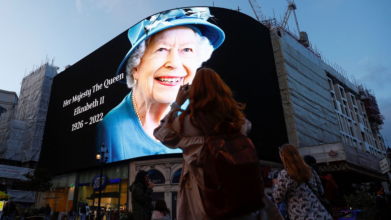 People take photos with their phones as an image of the Queen is displayed in London's Piccadilly Circus on September 8.