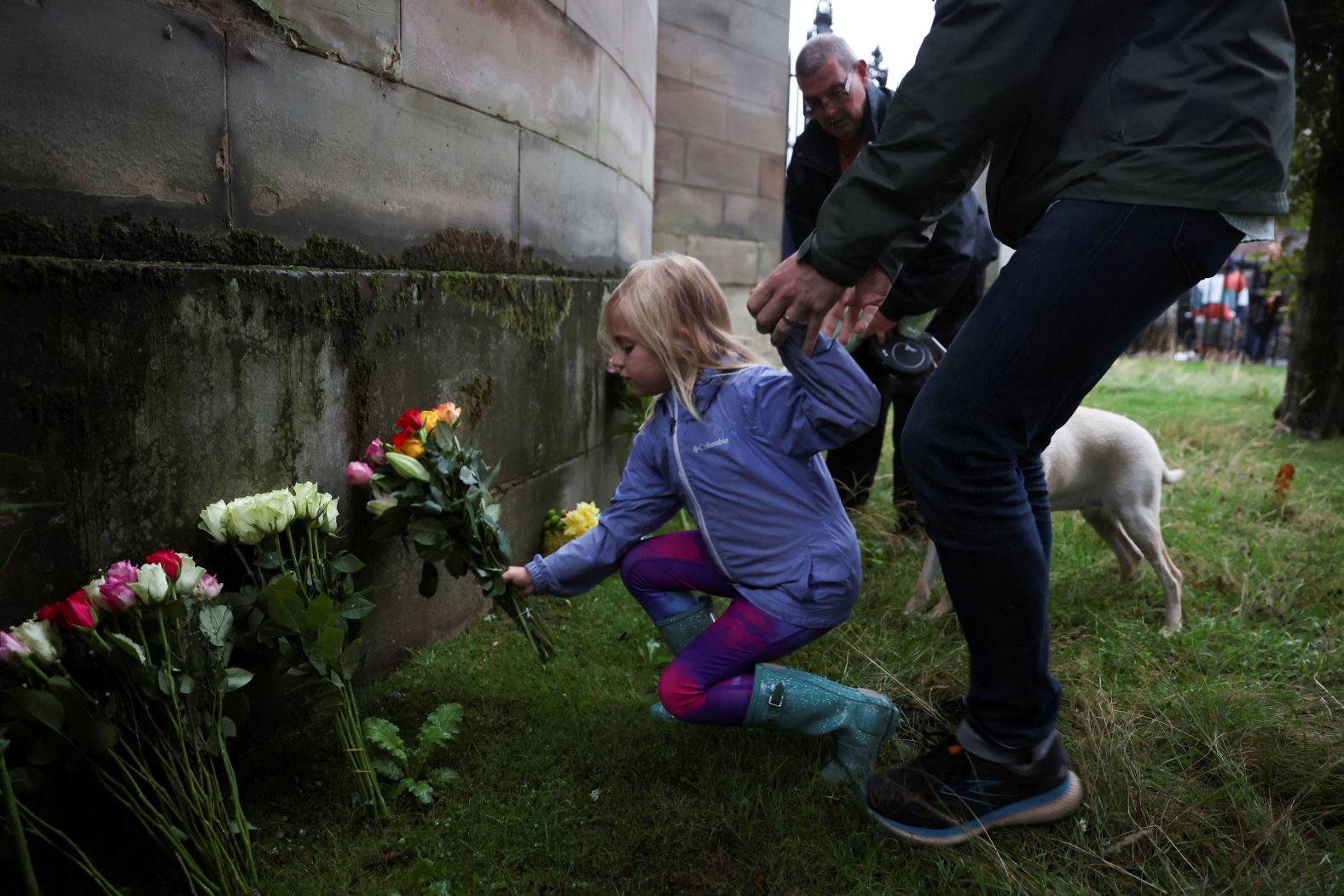 A child places flowers outside the Palace of Holyroodhouse in Edinburgh.