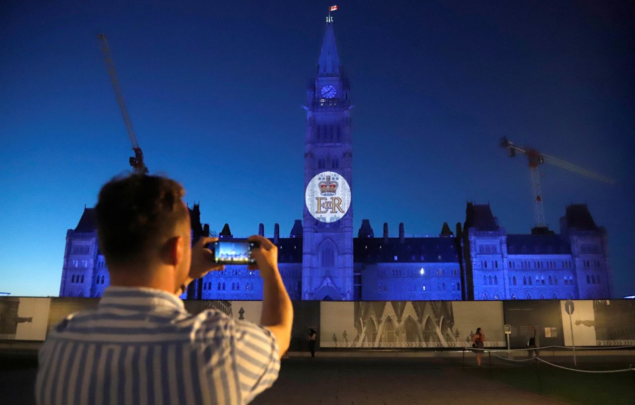 A man photographs the Queen's royal cypher as it is projected on the Peace Tower of the Parliament Building in Ottawa.