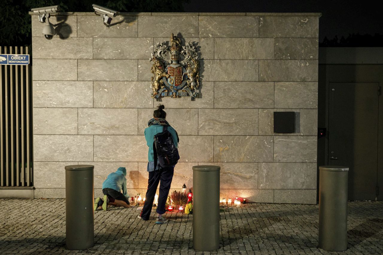 A girl lights candles near the fence of the British Embassy in Warsaw, Poland, a few hours after the announcement of the Queen's death.