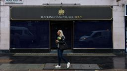 A well-wisher carrying a bouquet of flowers, on the first day of public mourning following the death of Queen Elizabeth II, passes the closed Buckingham Palace Shop with blacked-out windows in London, UK, on Friday, Sept. 9, 2022. Elizabeth IIs death at the age of 96 marks the start of a tumultuous 10 days for the UK that will see a queen buried, a nation mourn its longest-reigning monarch, and a new king proclaimed. Photographer: Hollie Adams/Bloomberg via Getty Images