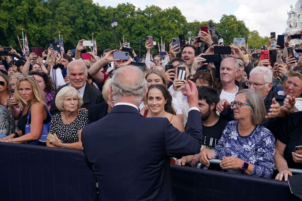 Charles greets well-wishers as he walks by the gates of Buckingham Palace on Friday.