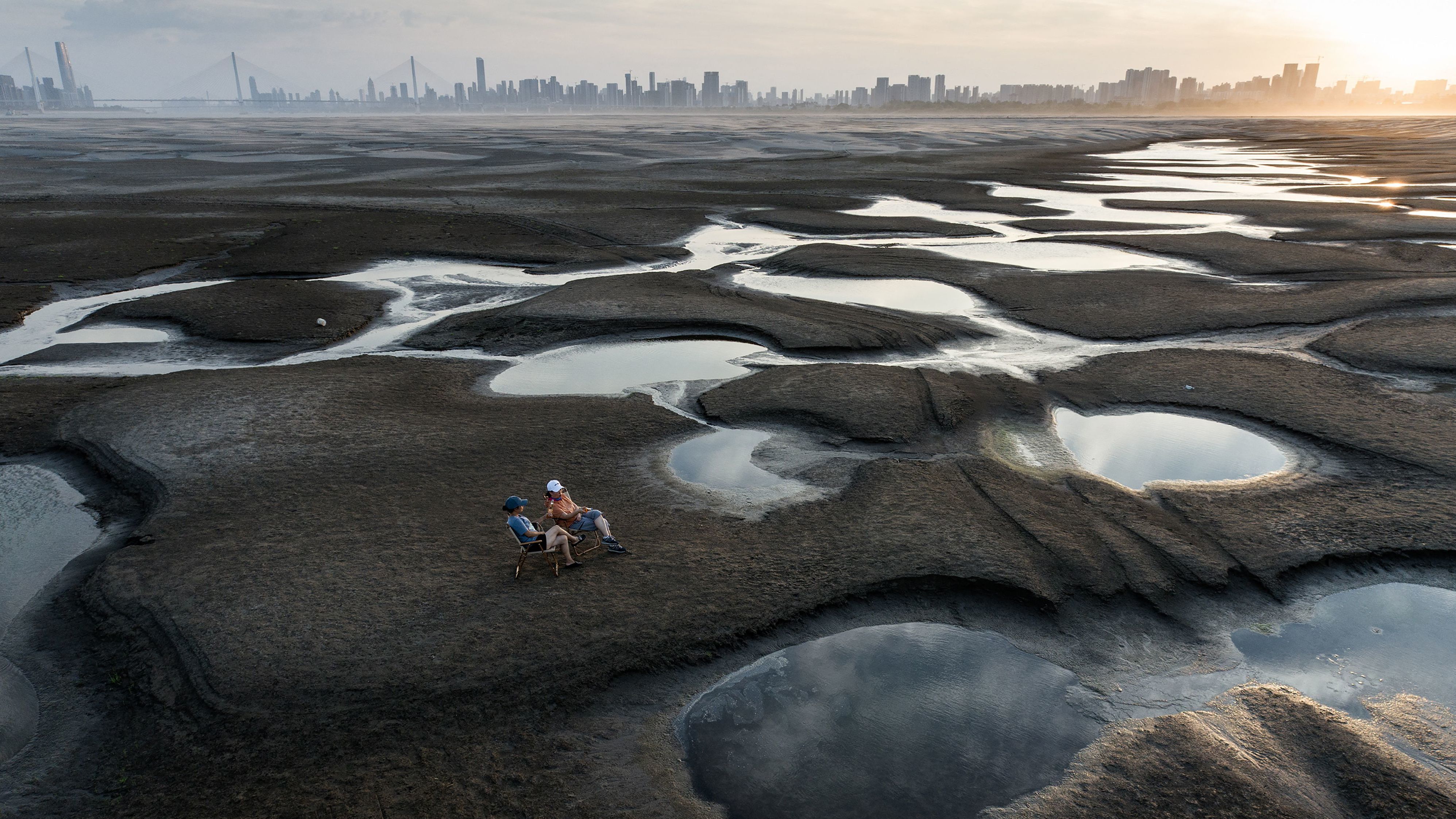 People sit on a parched river bed in Wuhan, China, on Friday, September 2.