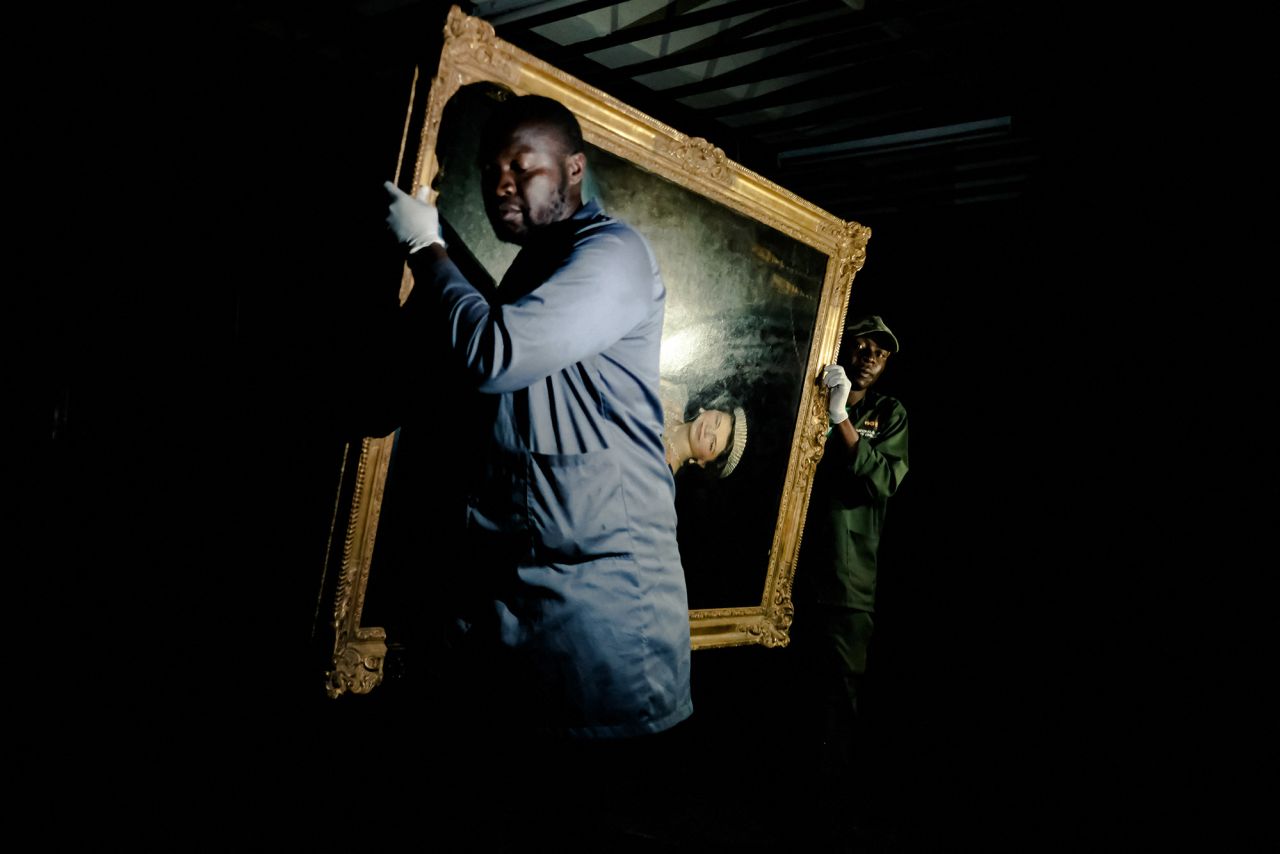 Staff carry a portrait of the Queen out of storage at the Zimbabwe National Art Gallery in Harare, Zimbabwe.