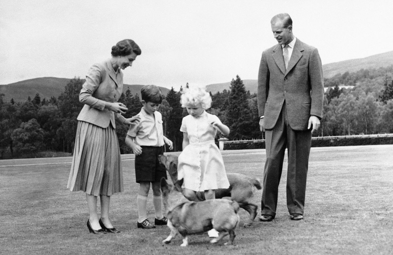 The Queen and her husband, Prince Philip, watch their children Prince Charles and Princess Anne play with their dogs during a family vacation at Balmoral Castle in 1955.