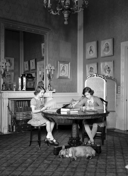 Elizabeth, right, and her sister, Princess Margaret, work at a desk while a corgi lies on the floor beside them at Windsor Castle in 1940. Elizabeth was officially gifted her own corgi by her parents on her 18th birthday in 1944.