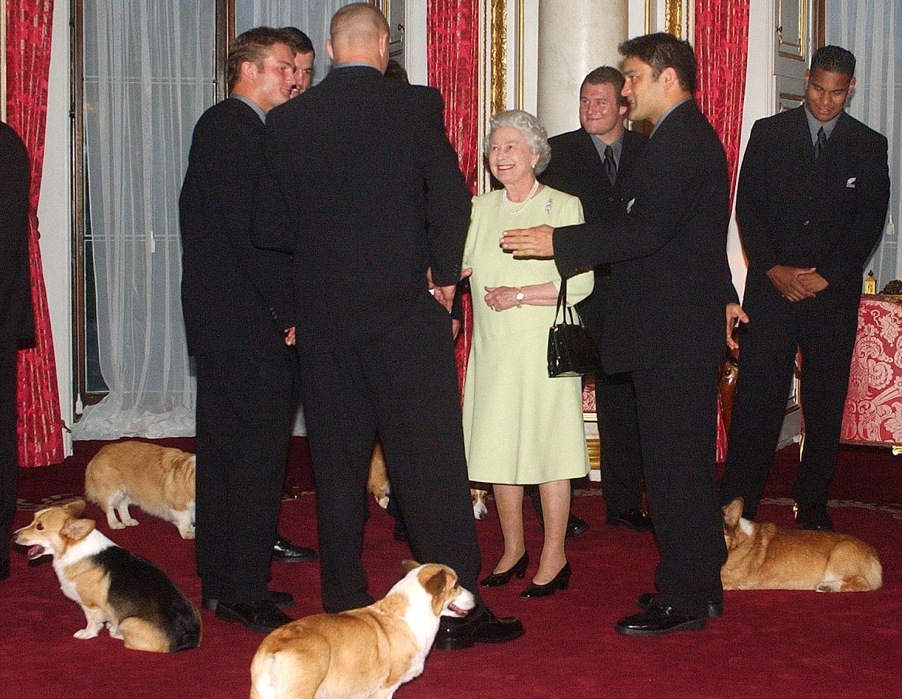 The Queen's dogs are all around her at Buckingham Palace as she meets the New Zealand rugby team in 2002.
