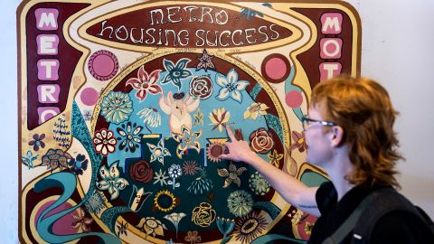 Jamie Wolff, a Hennepin County social worker, points to a mural in which each flower represents a person who found permanent housing.