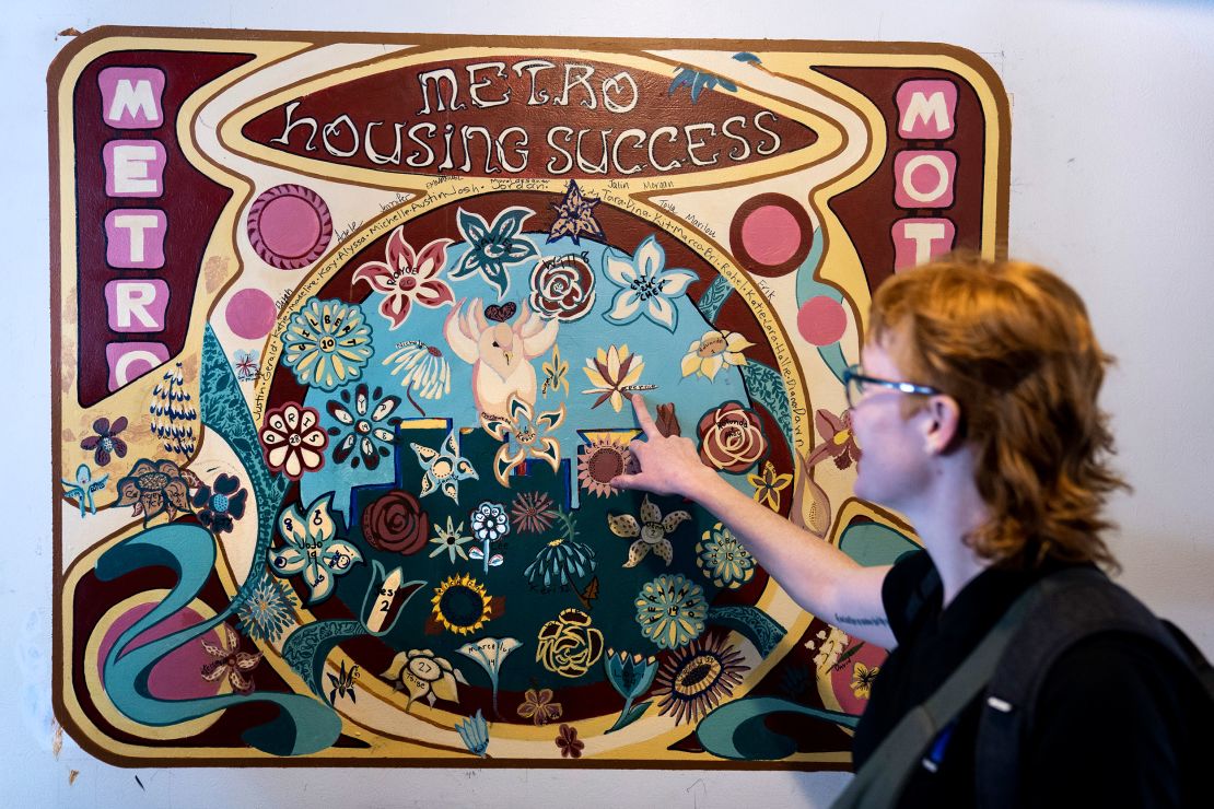 Jamie Wolff, a Hennepin County social worker, points to a mural in which each flower represents a person who found permanent housing.