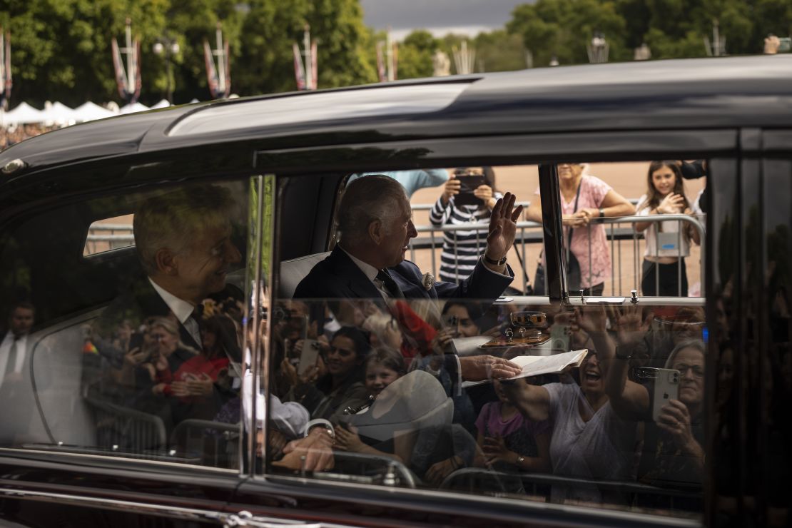 King Charles III greets supporters as he arrives at Buckingham Palace.