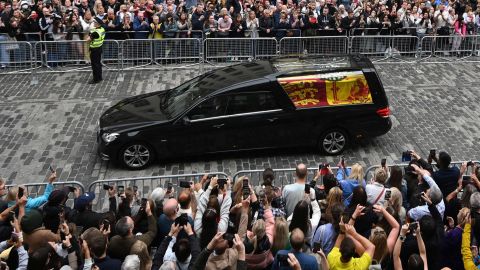 Members of the public watch the hearse carrying the coffin of Queen Elizabeth II as it is driven through Edinburgh toward the Palace of Holyroodhouse on Sunday
