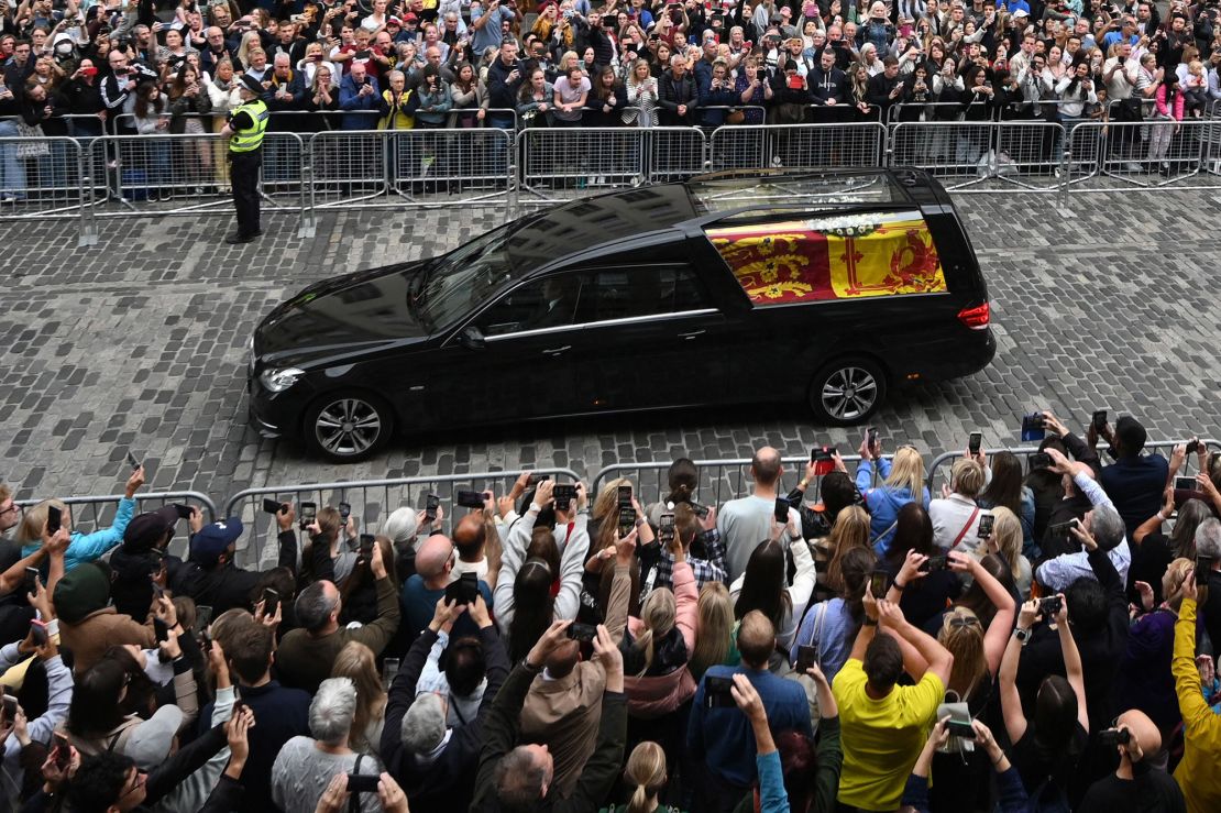 Members of the public watch the hearse carrying the coffin of Queen Elizabeth II as it is driven through Edinburgh toward the Palace of Holyroodhouse on Sunday