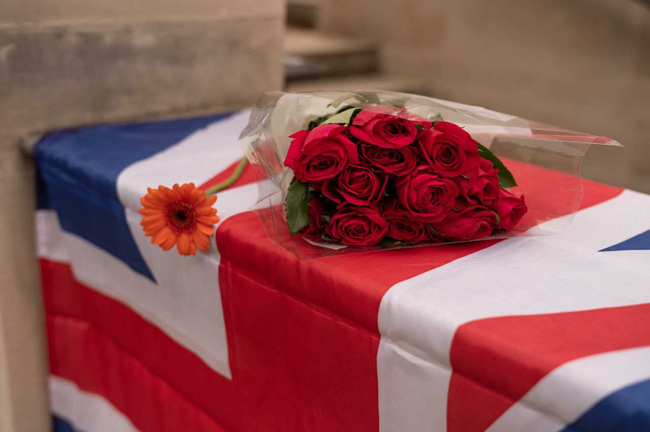 A bouquet of roses rests on a Union Jack flag in London.