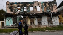 This photograph taken on September 11, 2022, shows a couple wheeling suitcases as they walk in front of a destroyed building in Izyum, Kharkiv Region, eastern Ukraine, amid the Russian invasion of Ukraine. - Ukraine forces said that their lightning counter-offensive took back more ground in the past 24 hours, as Russia replied with strikes on some of the recaptured ground. The territorial shifts were one of Russia's biggest reversals since its forces were turned back from Kyiv in the earliest days of the nearly seven months of fighting, yet Moscow signalled it was no closer to agreeing a negotiated peace. (Photo by Juan BARRETO / AFP) (Photo by JUAN BARRETO/AFP via Getty Images)