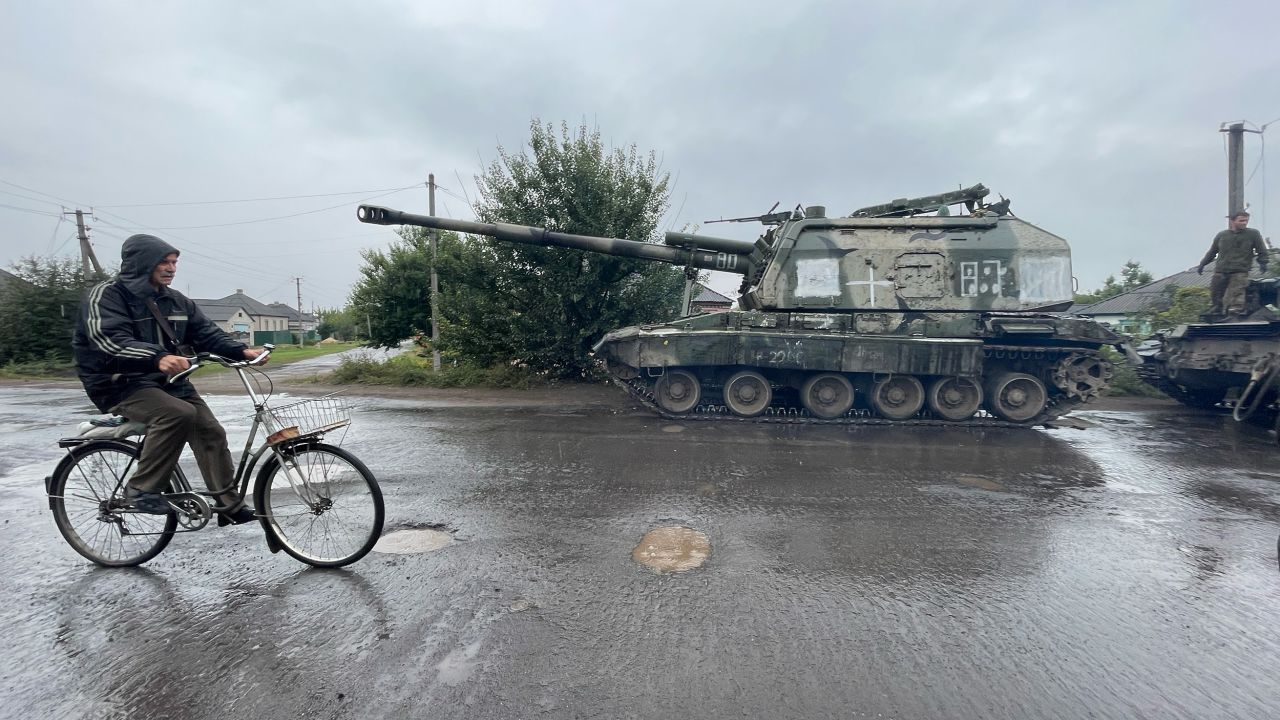 A man cycles past an abandoned Russian self-propelled artillery vehicle in Izium.