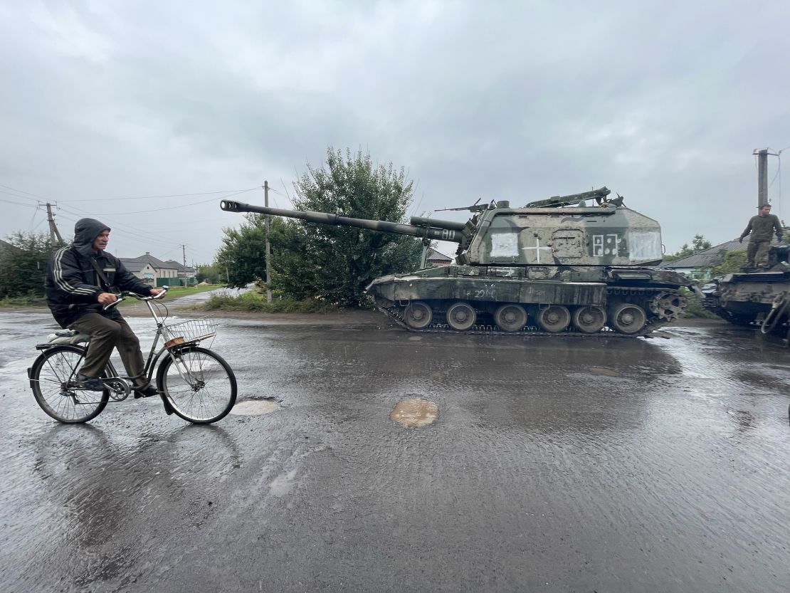 A man cycles past an abandoned Russian self-propelled artillery vehicle in Izium.