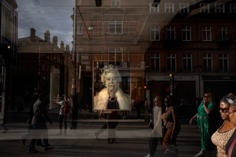 People in London walk past a portrait of the Queen on September 12.