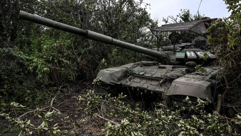 Sebuah tank Rusia yang ditinggalkan duduk di vegetasi di sebuah desa di pinggiran Izium, Ukraina, pada hari Minggu.