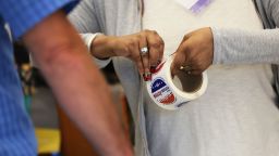 A poll worker peels voting stickers for a voter during the June Primary Election at Brooklyn Central Library on June 28, 2022 in New York, New York.