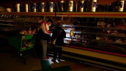 FILE - In this Feb. 16, 2021, file photo, customers use the light from a cell phone to look in the meat section of a grocery store in Dallas. Even though the store lost power, it was open for cash only sales. (AP Photo/LM Otero, File)