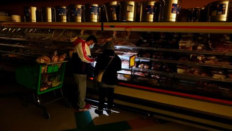Customers shop at a Dallas grocery by the light of their cell phones in February 2021 during an extreme cold blast that knocked power out for tens of millions in Texas. 