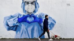 A man walks his dog past a mural depicting a frontline worker amid the spread of the coronavirus disease (COVID-19) in Dublin, Ireland, January 12, 2022. REUTERS/Clodagh Kilcoyne